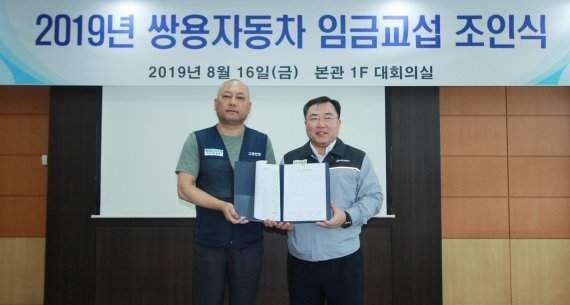 예병태 쌍용자동차 대표이사(오른쪽)와 정일권 노동조합위원장이 2019년 8월 평택 본사에서 임금협상 합의서에 서명한 뒤 기념촬영을 하고 있다. (사진=쌍용차)