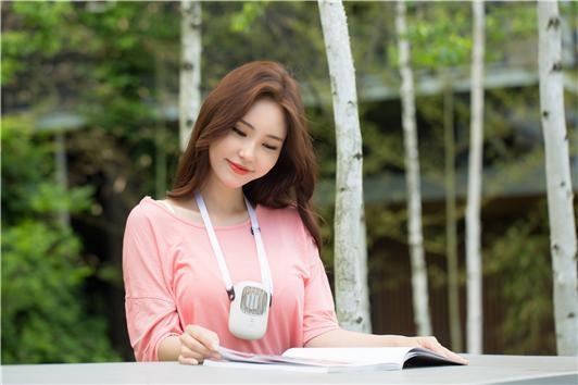 토큰 모델이 책을 읽으면서 목걸이선풍기를 사용하고 있다.