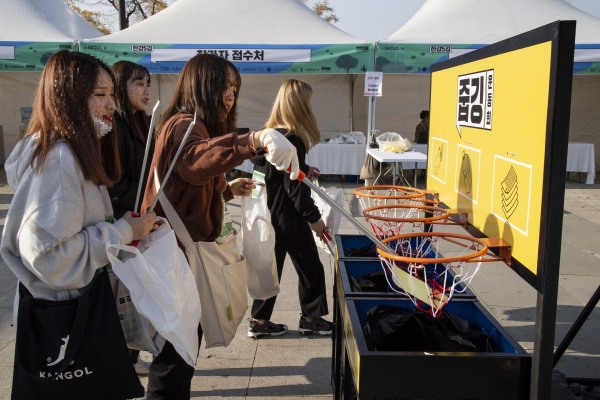 한강 줍깅 참가자들이 이색 쓰레기통에 주워온 쓰레기를 직접 분리배출 하고 있다 한강 줍깅 참가자들이 이색 쓰레기통에 주워온 쓰레기를 직접 분리배출 하고 있다
